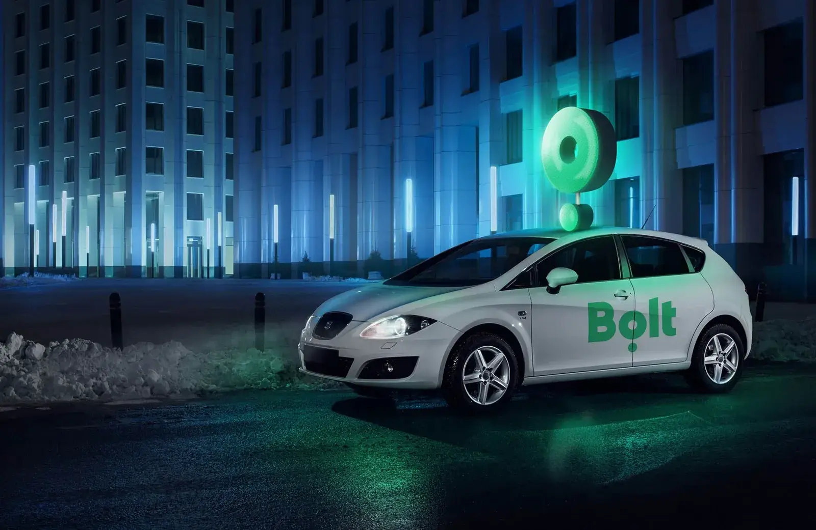 Автомобіль Bolt із зеленим логотипом біля освітленої офісної будівлі вночі