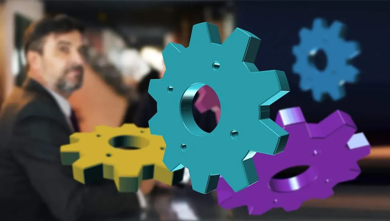 Colorful gears against a blurred businessman in the background