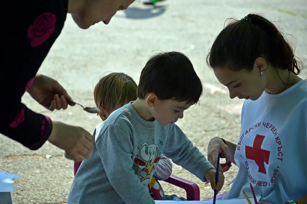 A Red Cross volunteer drawing with children