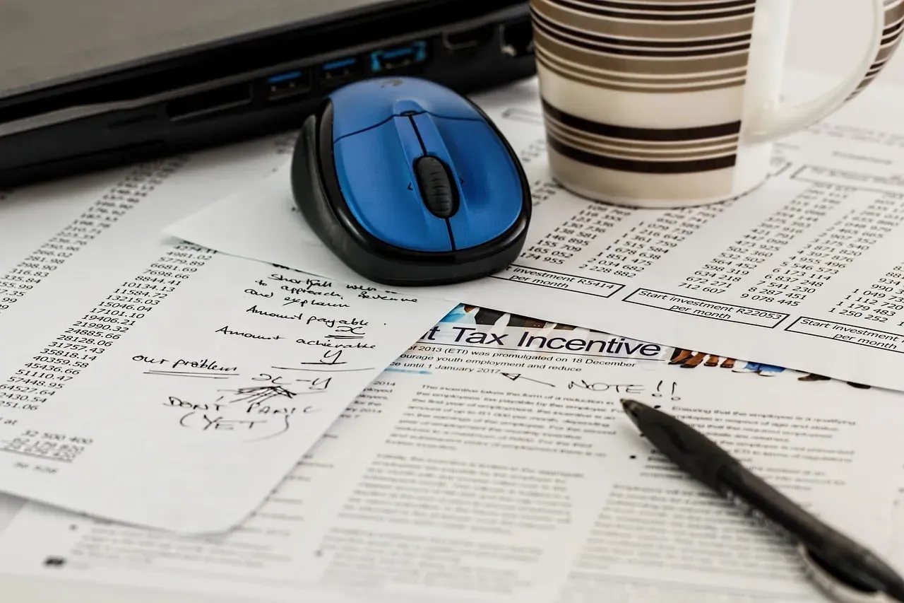 Tax documents with calculations and handwritten notes, a computer mouse and a pen