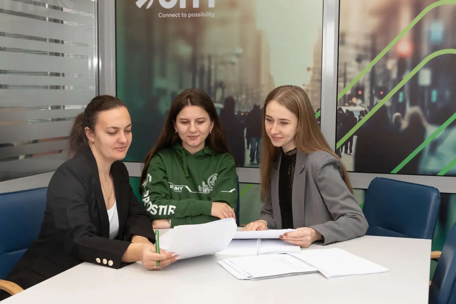 Три фахівчині UHY Prostir переглядають документи за столом у переговорній