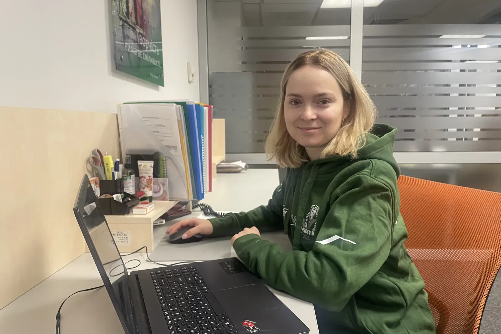 A UHY Prostir specialist in a branded hoodie working on a laptop in the office
