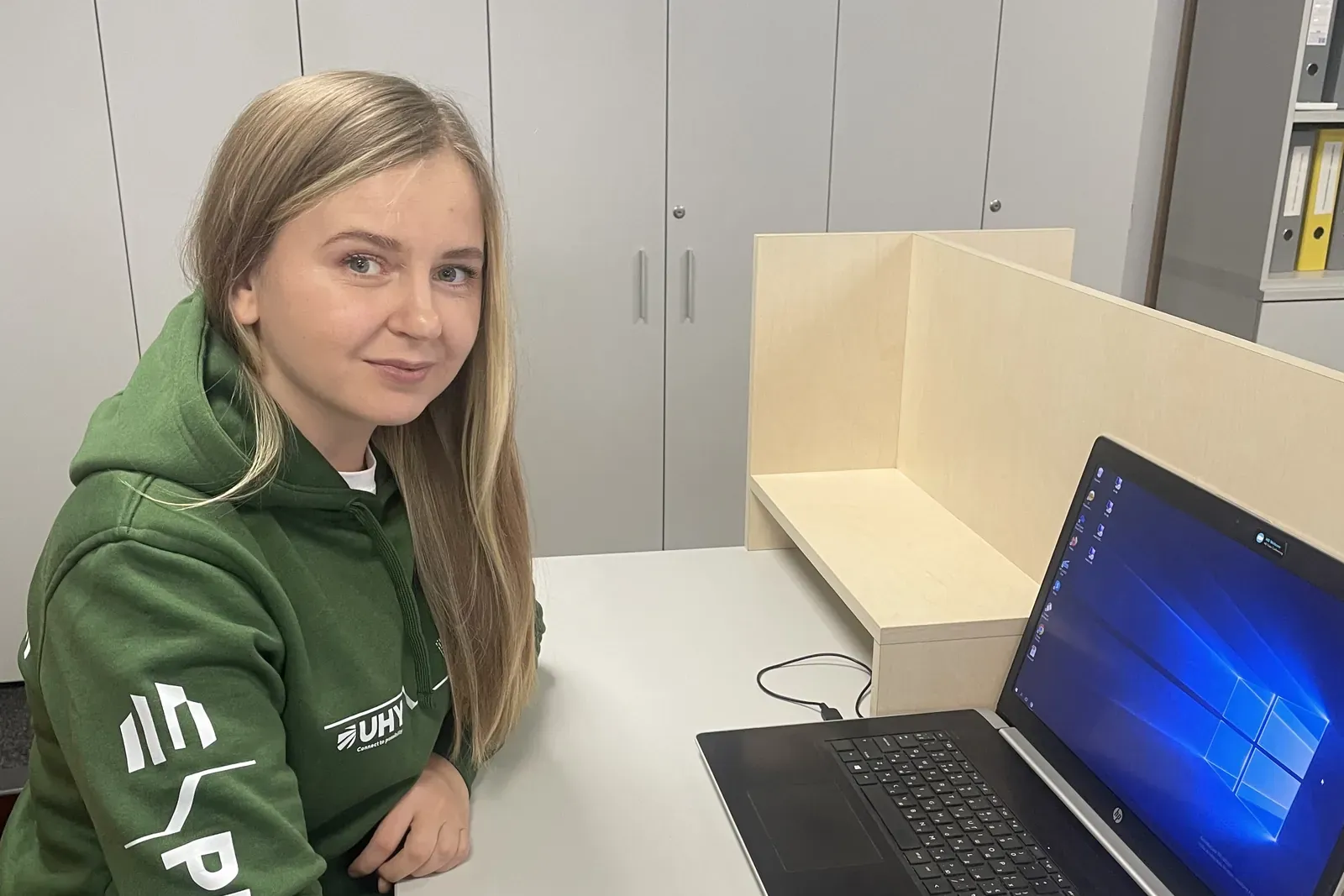 Сотрудница UHY Prostir в фирменном худи за ноутбуком на рабочем месте